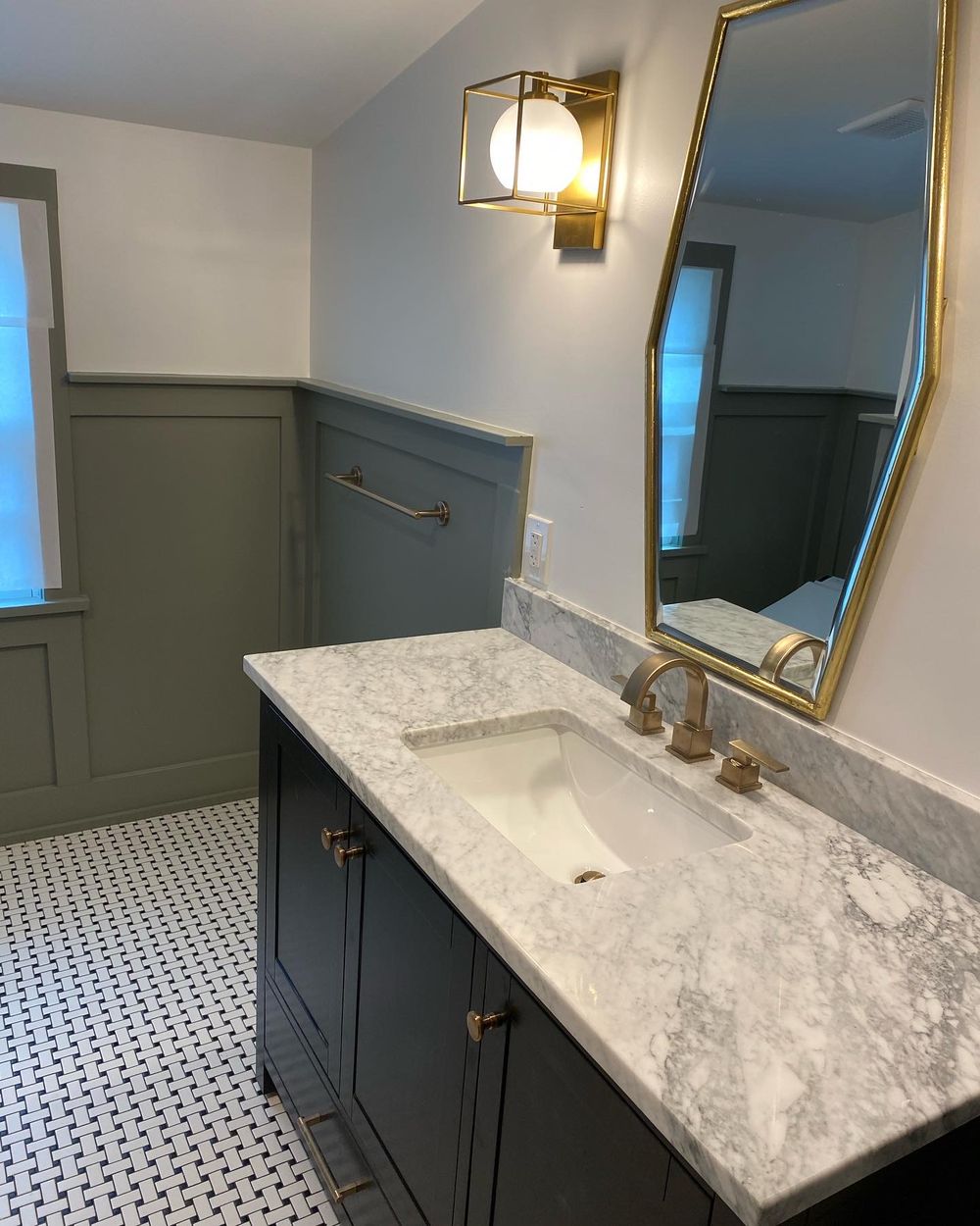 Bathroom vanity with marble top, brass fixtures, and hex tile floor