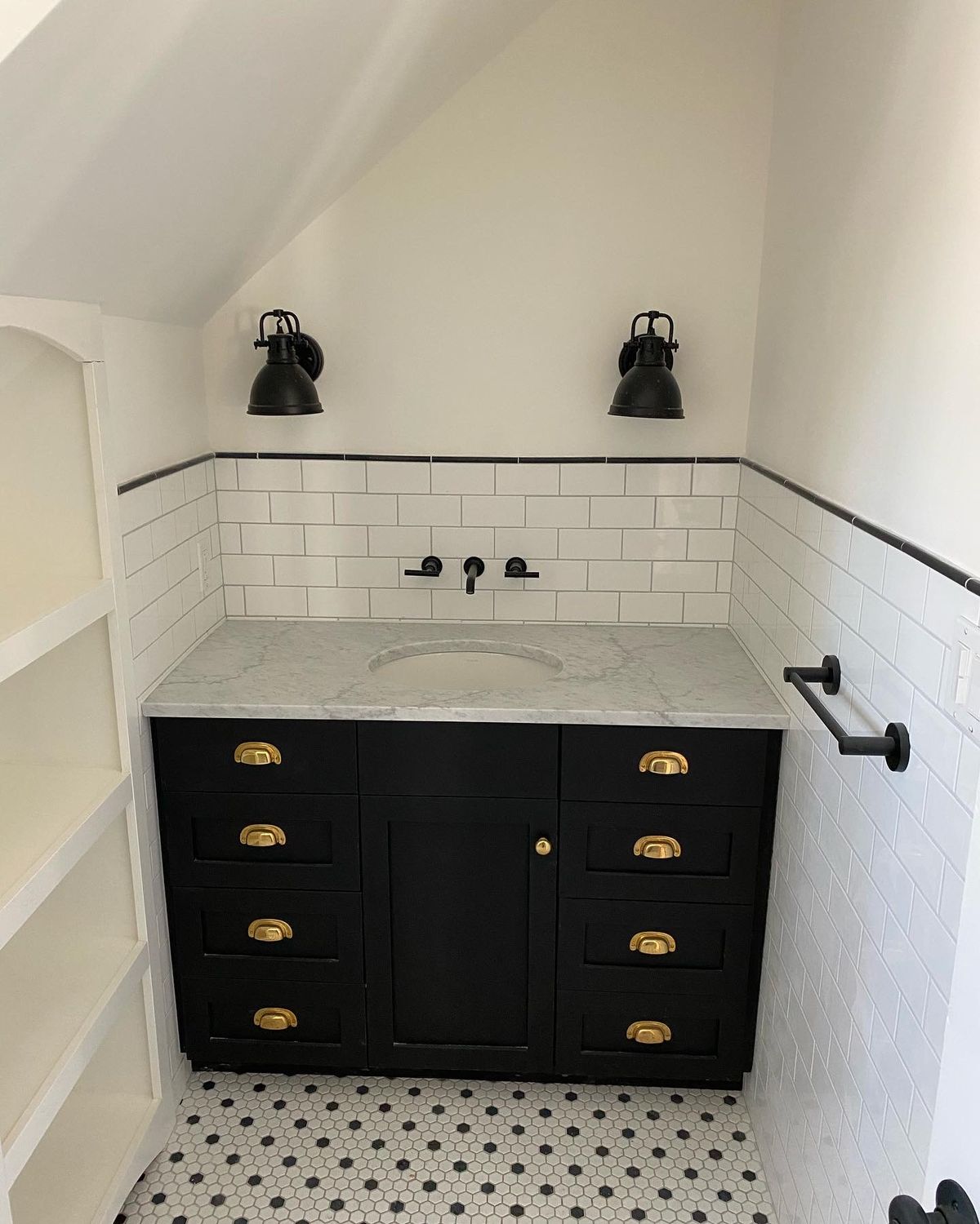 Remodeled bathroom with a black vanity, brass pulls, and white subway tile