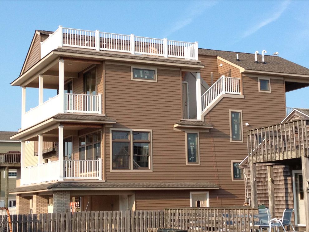Three-story custom home with stacked balconies and a rooftop deck