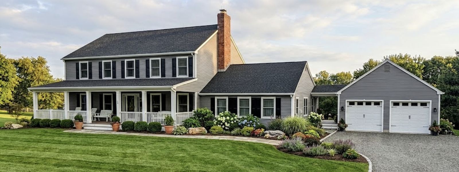 Two-story colonial custom home with a covered front porch and detached garage