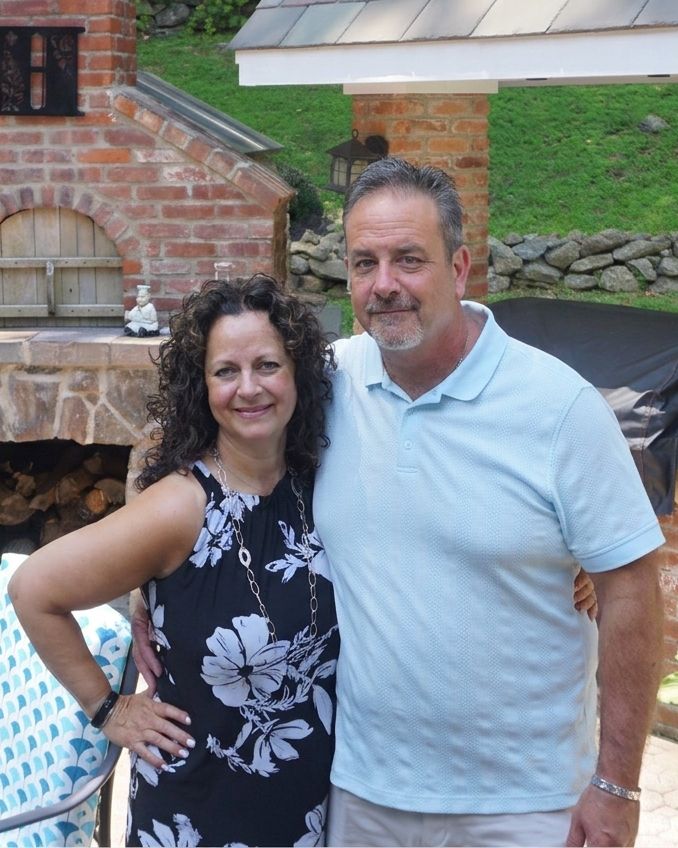 Tony Haddad (right), founder of Hadco Builders, on a patio beside a brick oven